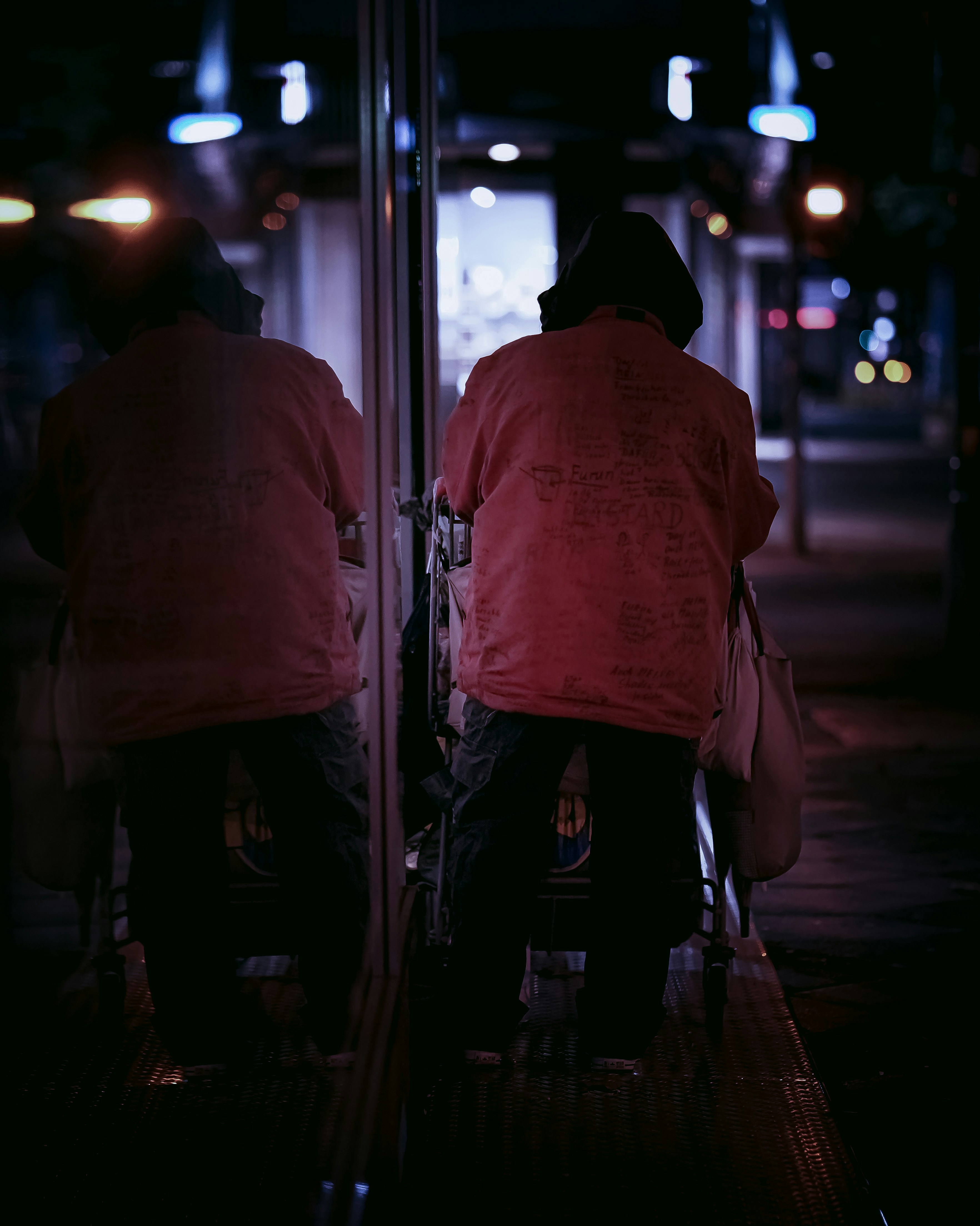 man in orange hoodie standing in front of glass window