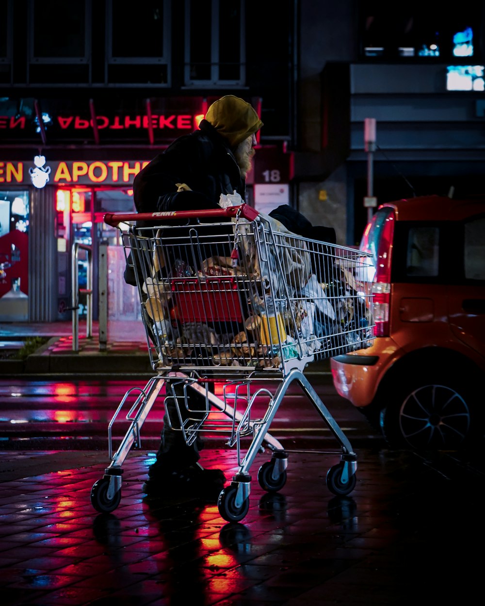 woman in black jacket riding red and silver shopping cart