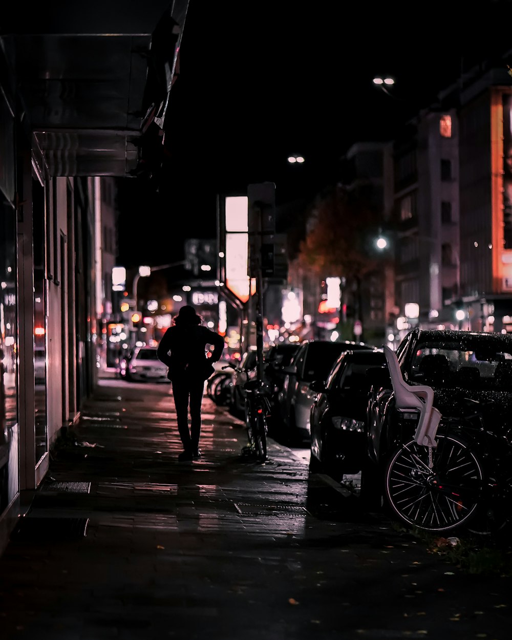 검은 재킷을 입은 남자가 밤에 보도를 걷고 있습니다.