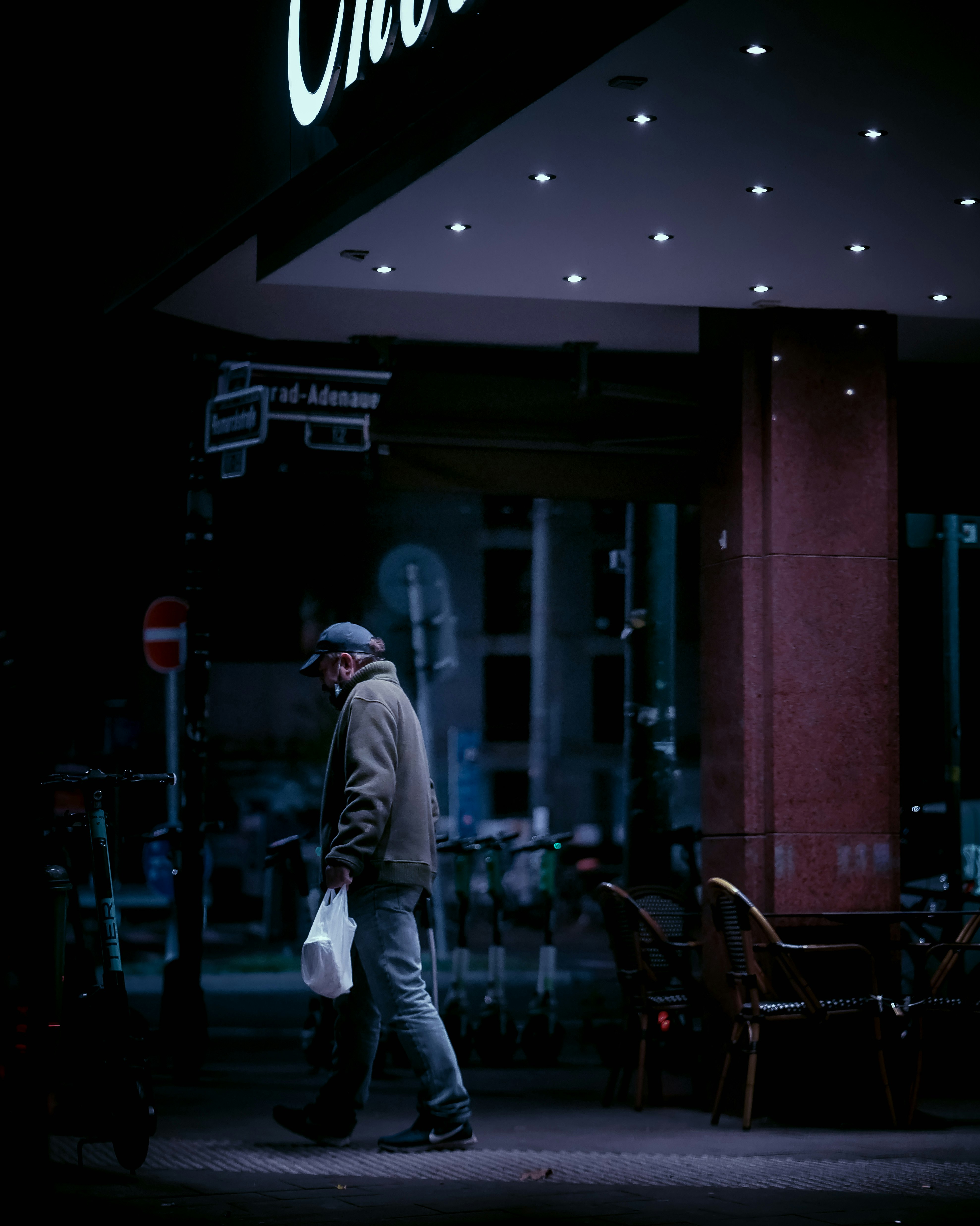 man in gray hoodie walking on sidewalk during night time