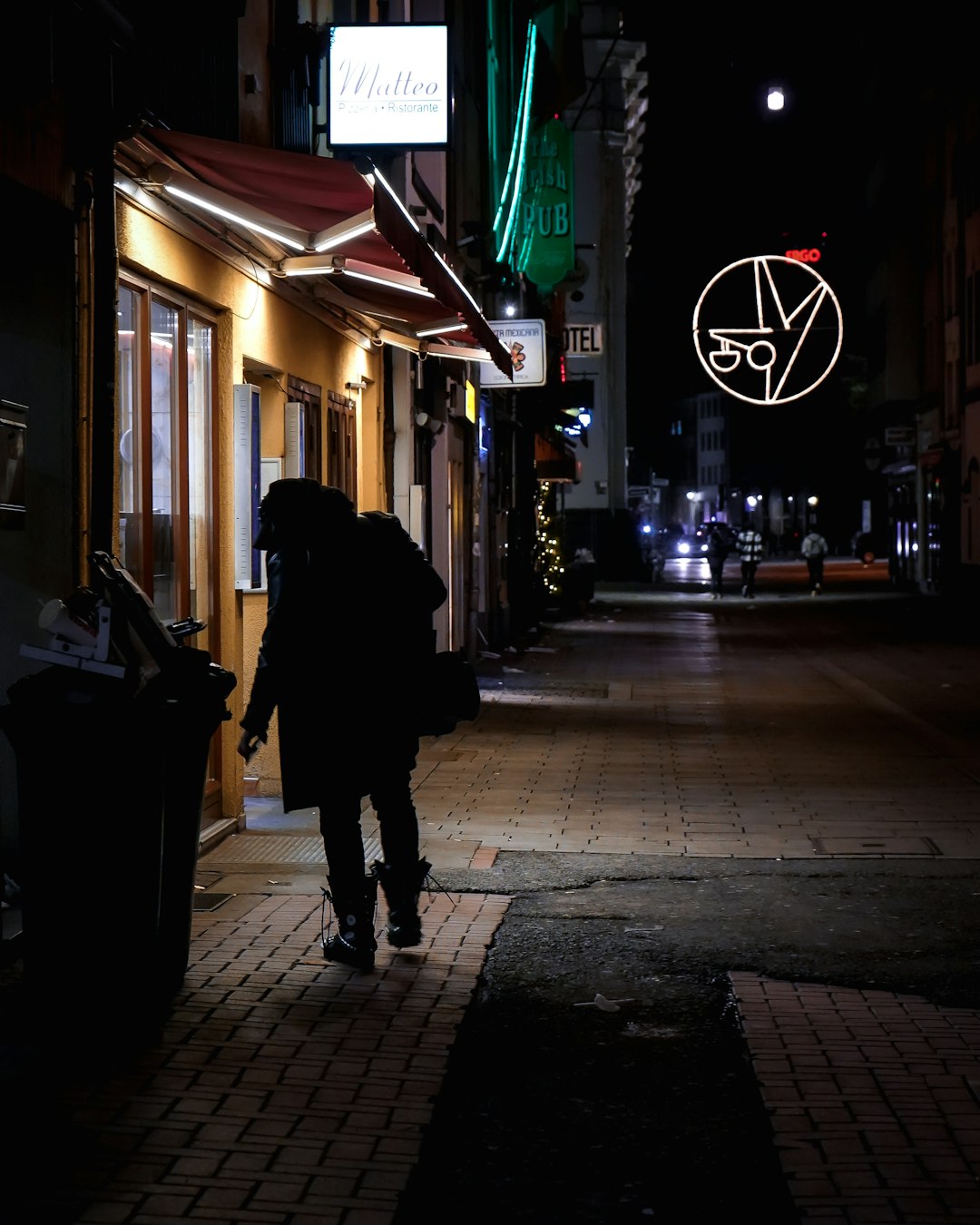 man in black jacket walking on sidewalk during night time