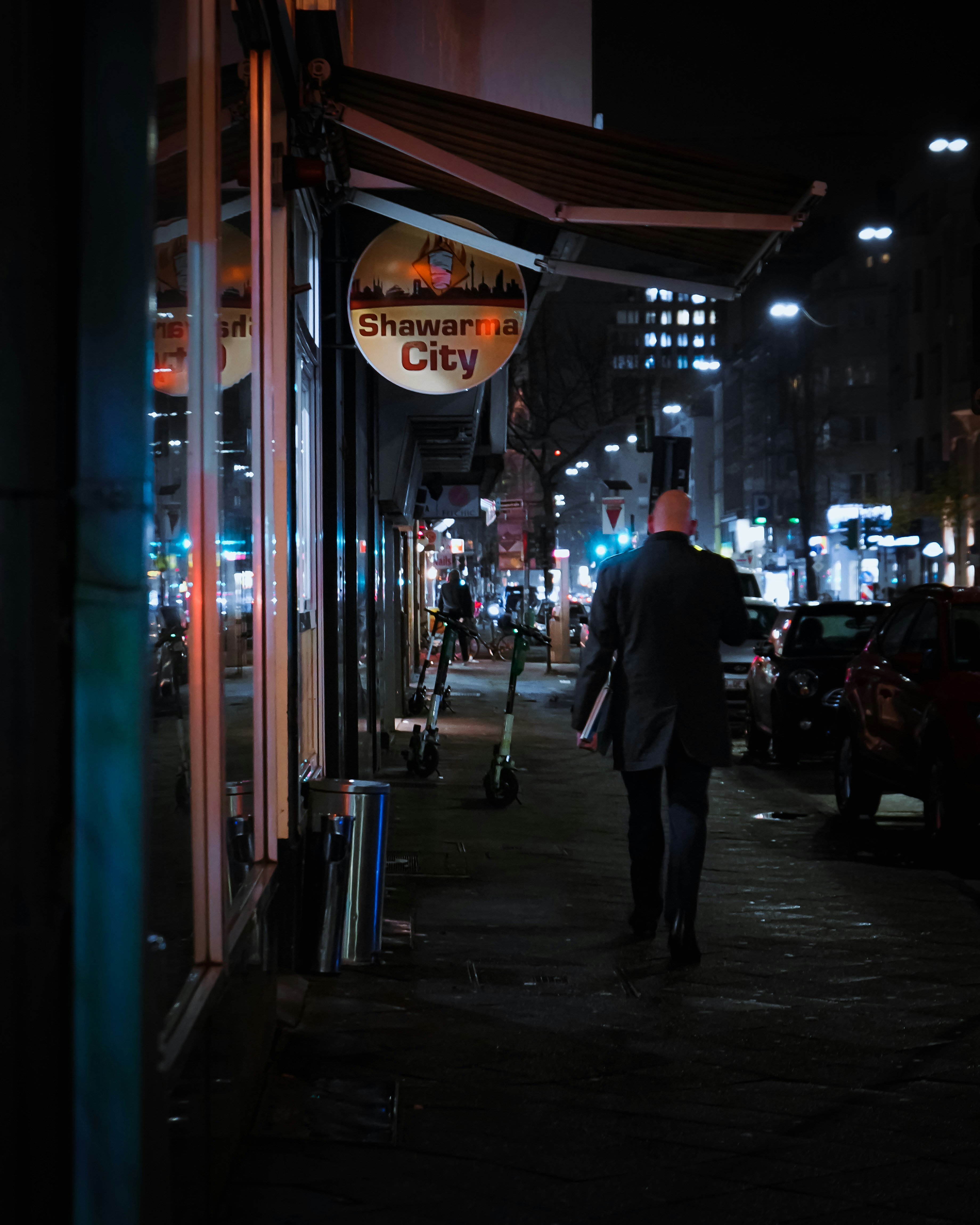 man in black jacket walking on sidewalk during night time