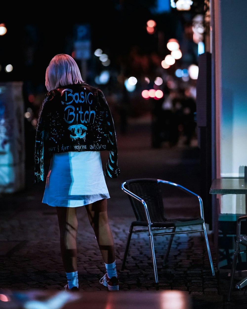 woman in white mini skirt standing near glass window