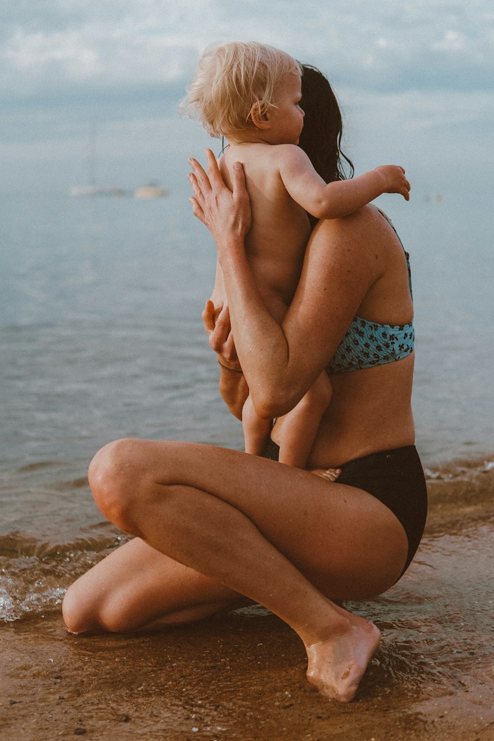 woman in blue and black polka dot bikini sitting on beach shore during daytime