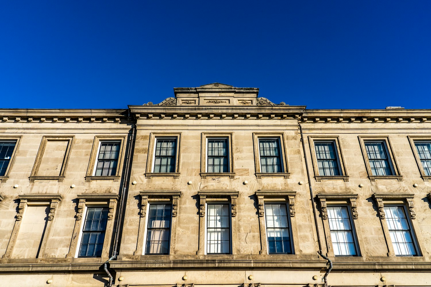 beige concrete building under blue sky during daytime by chris robert