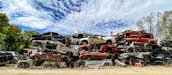 Stacked scrap cars ready for recycling with the Toronto skyline blurred in the background.