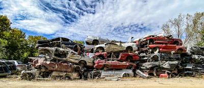 Stacked scrap cars ready for pickup with our branded tow truck in the background.