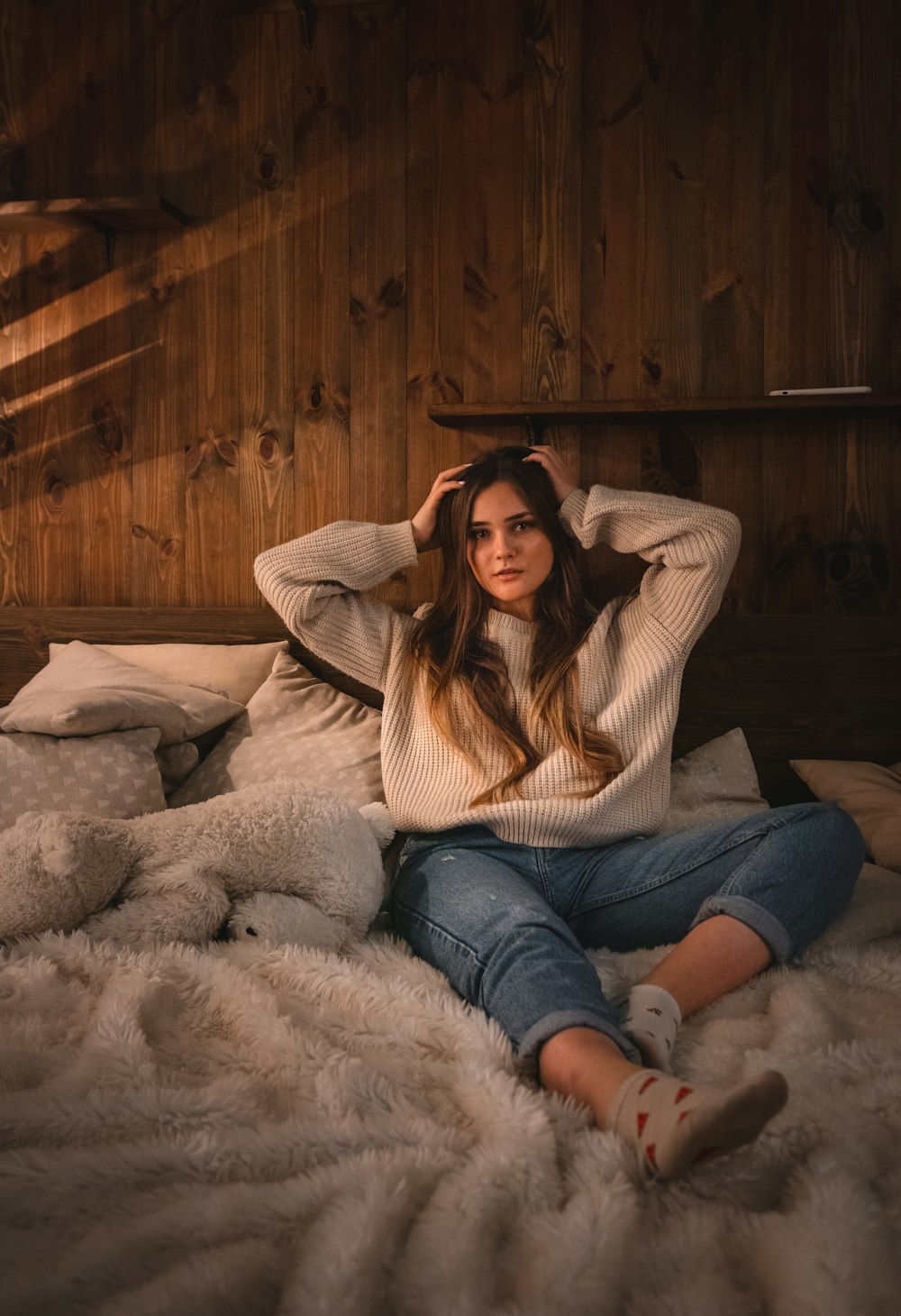 woman in brown jacket and blue denim jeans sitting on white fur textile