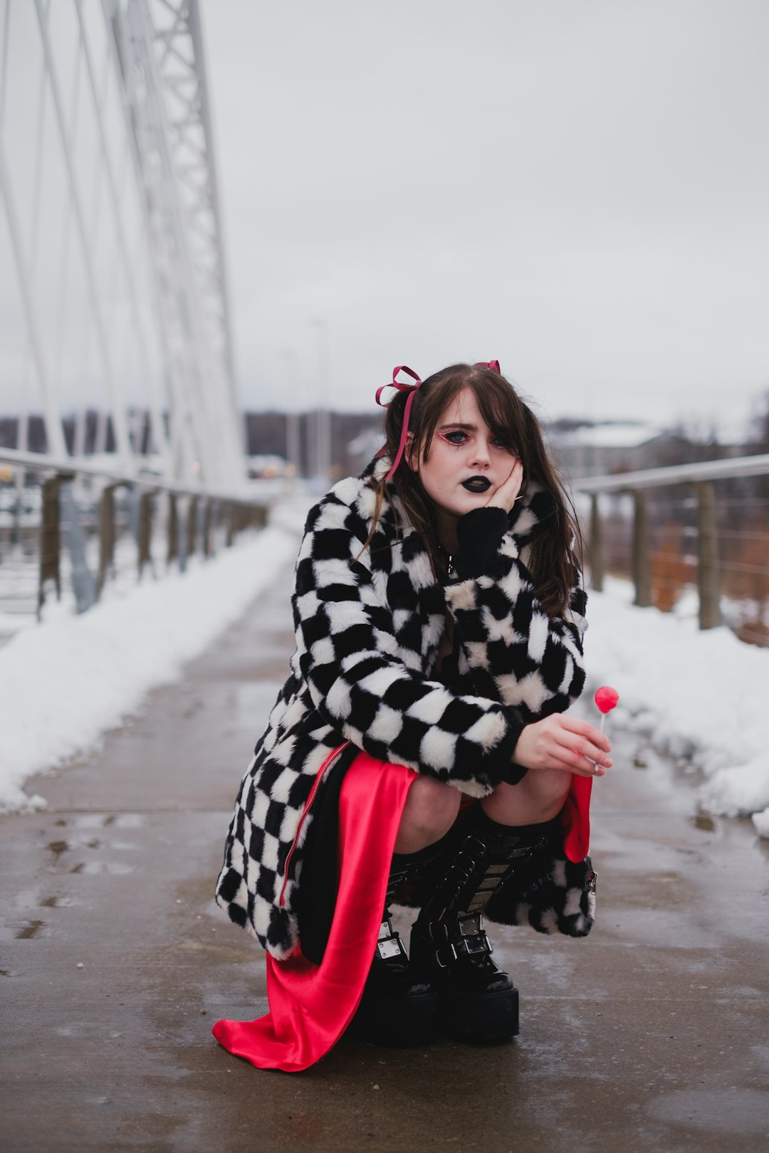 woman in black and white checkered coat and red pants standing on snow covered ground during