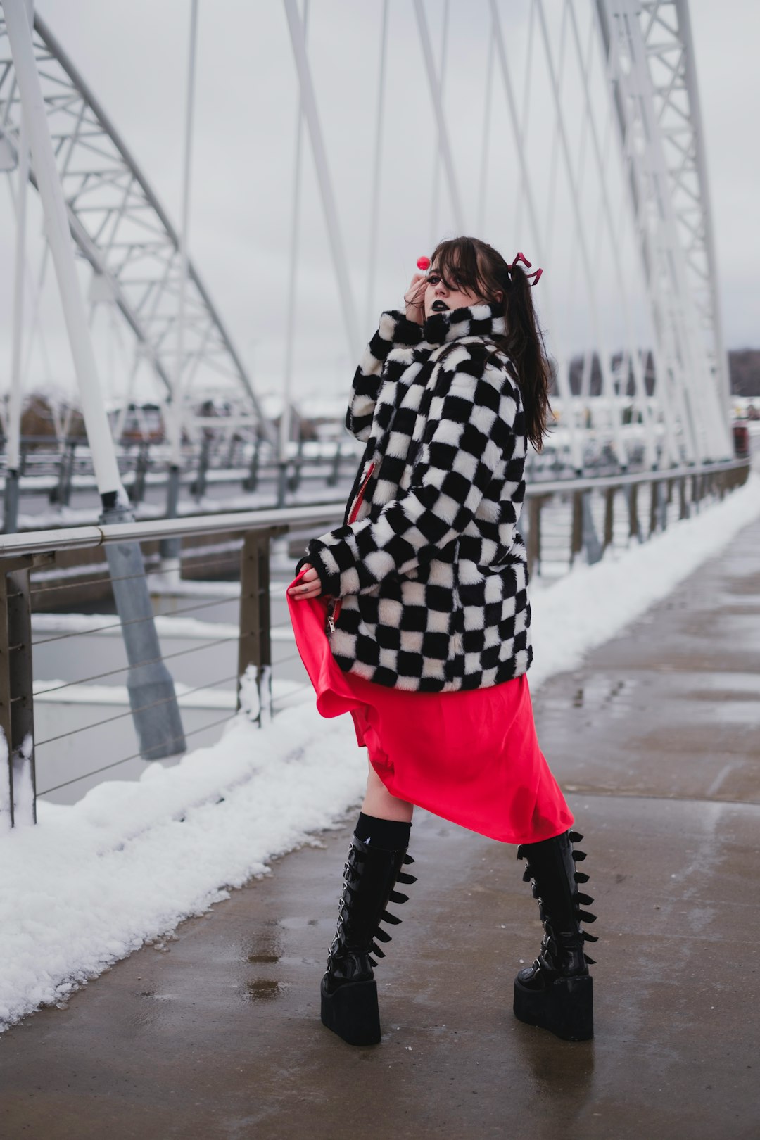 woman in black and white long sleeve shirt and pink skirt standing on bridge during daytime