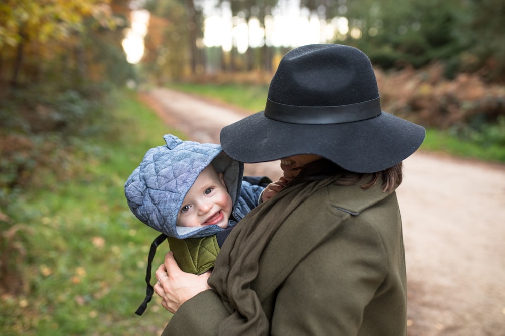 Femme en manteau marron portant bébé en bonnet en tricot bleu