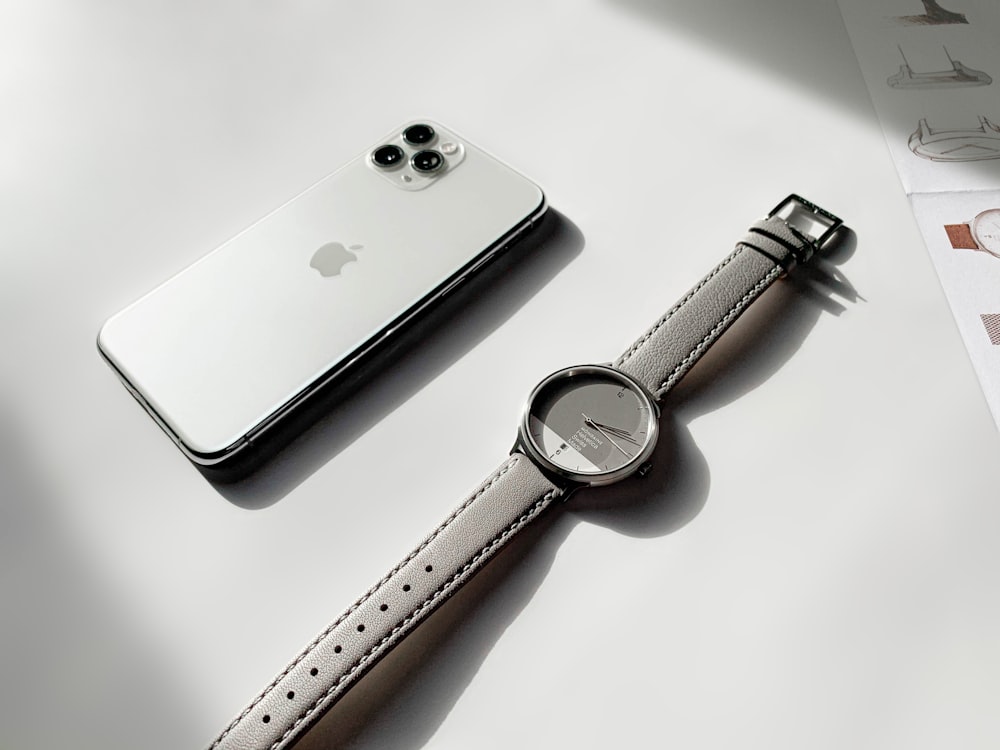 iPhone 6 plateado junto a Apple Watch plateado con correa de cuero marrón