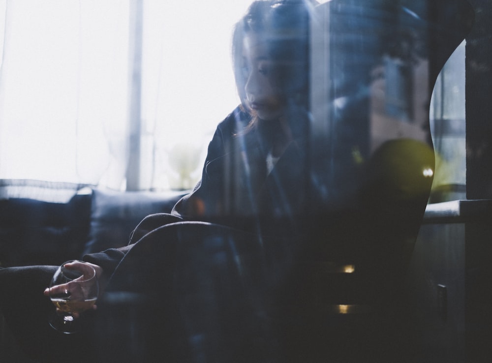 man in black jacket sitting beside window