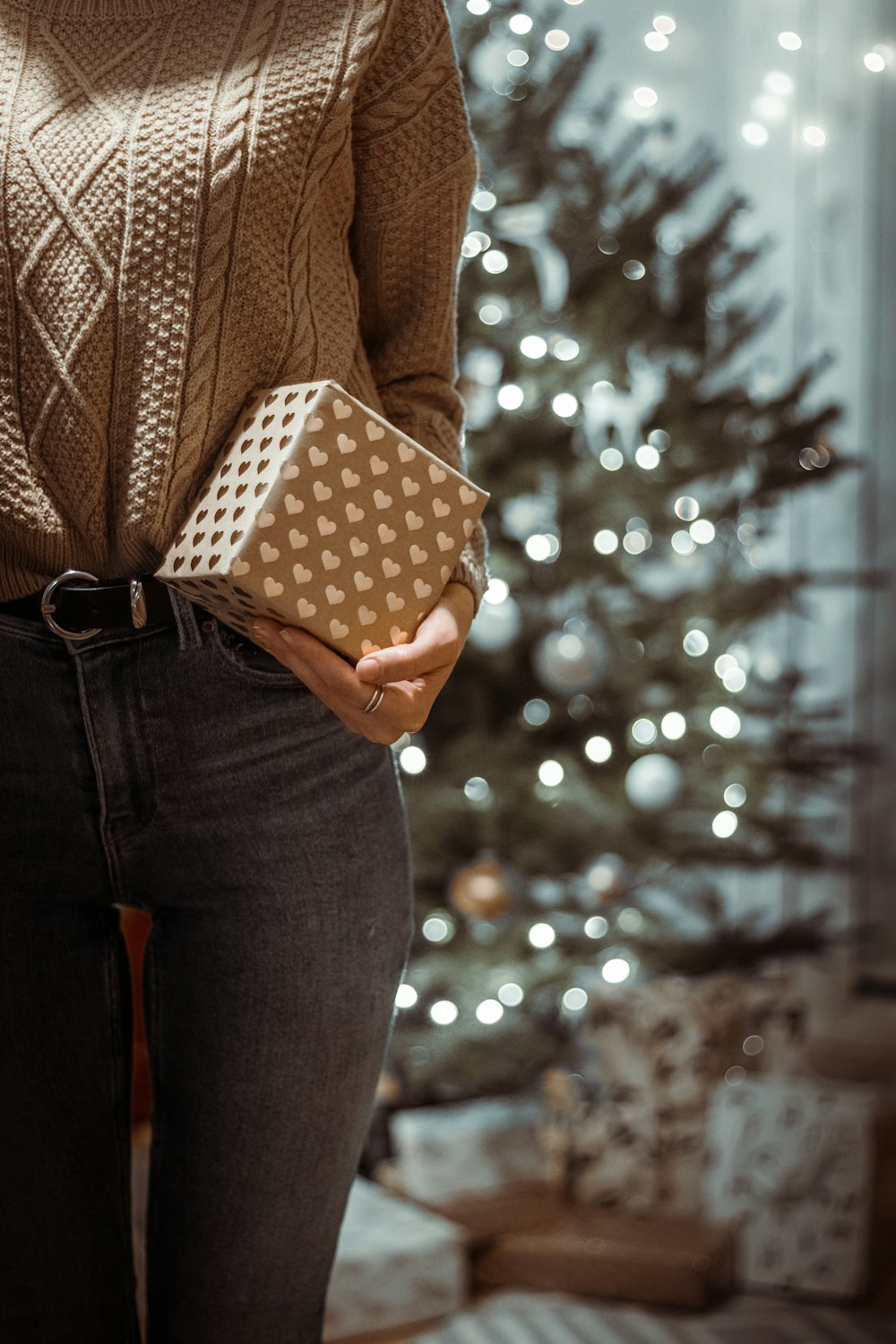 woman in brown sweater holding white and black polka dot box