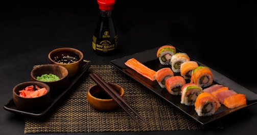 sushi on black ceramic plate beside sauce bottle