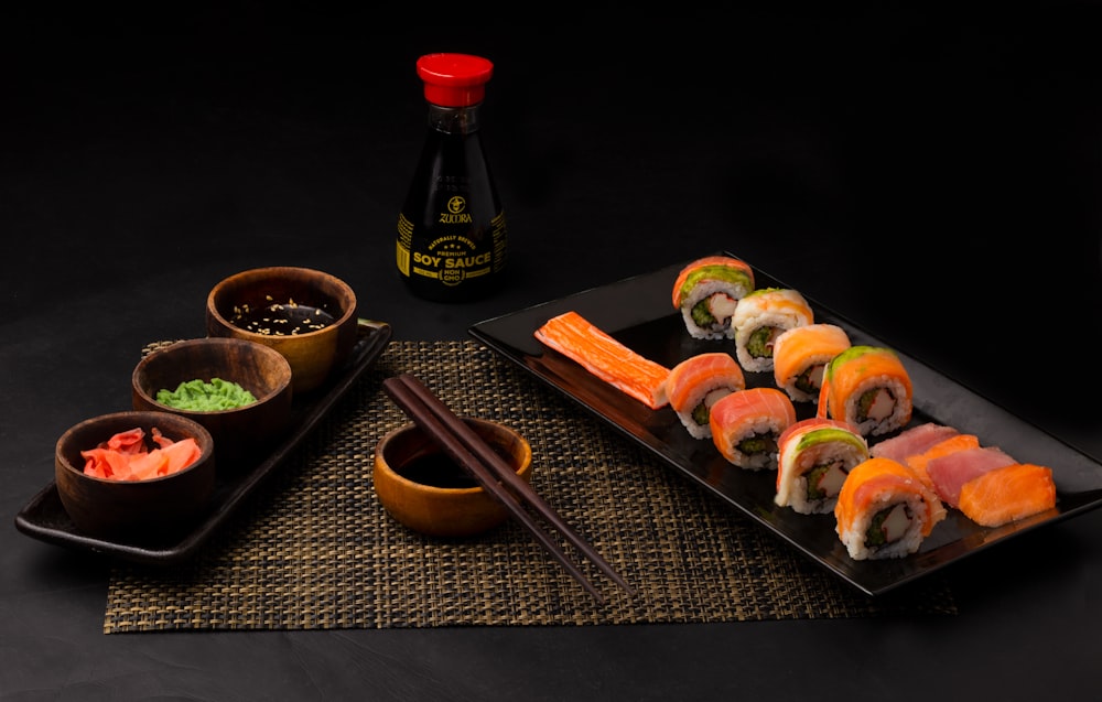 Sushi auf schwarzem Keramikteller neben Soßenflasche