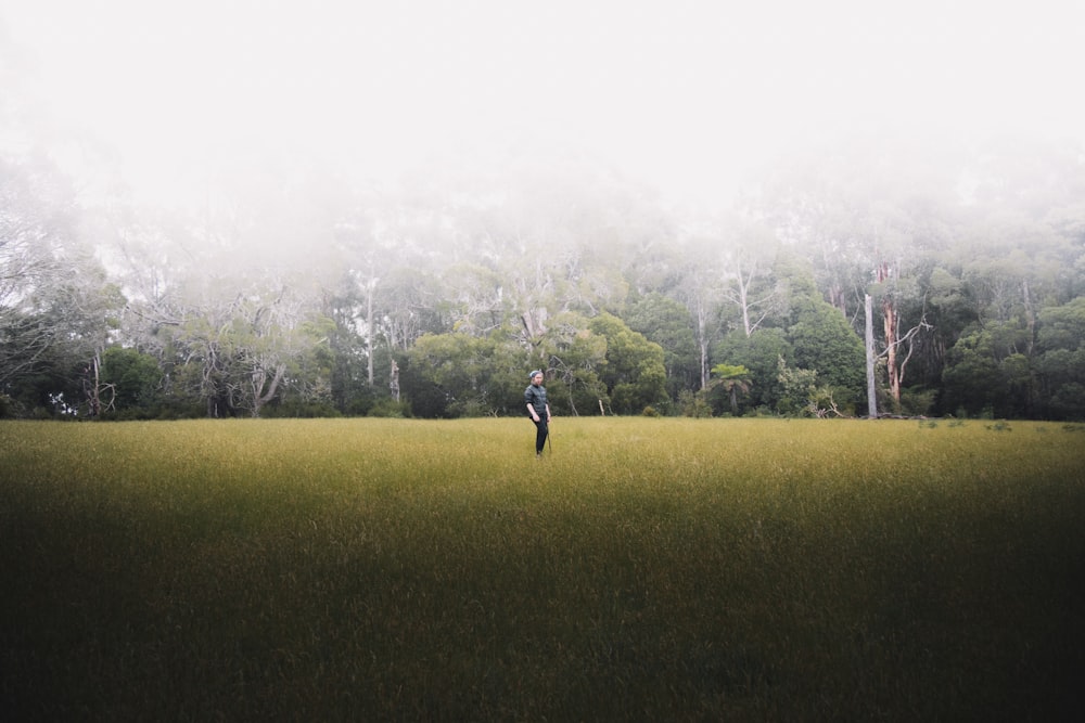 person in black jacket standing on green grass field during daytime