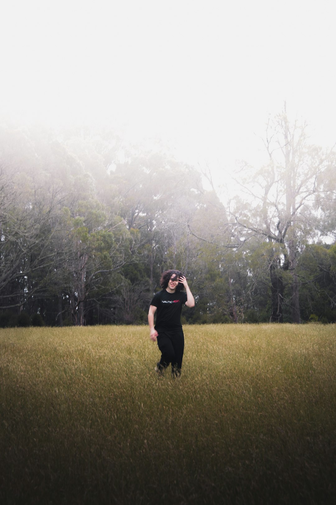 woman in black coat standing on green grass field