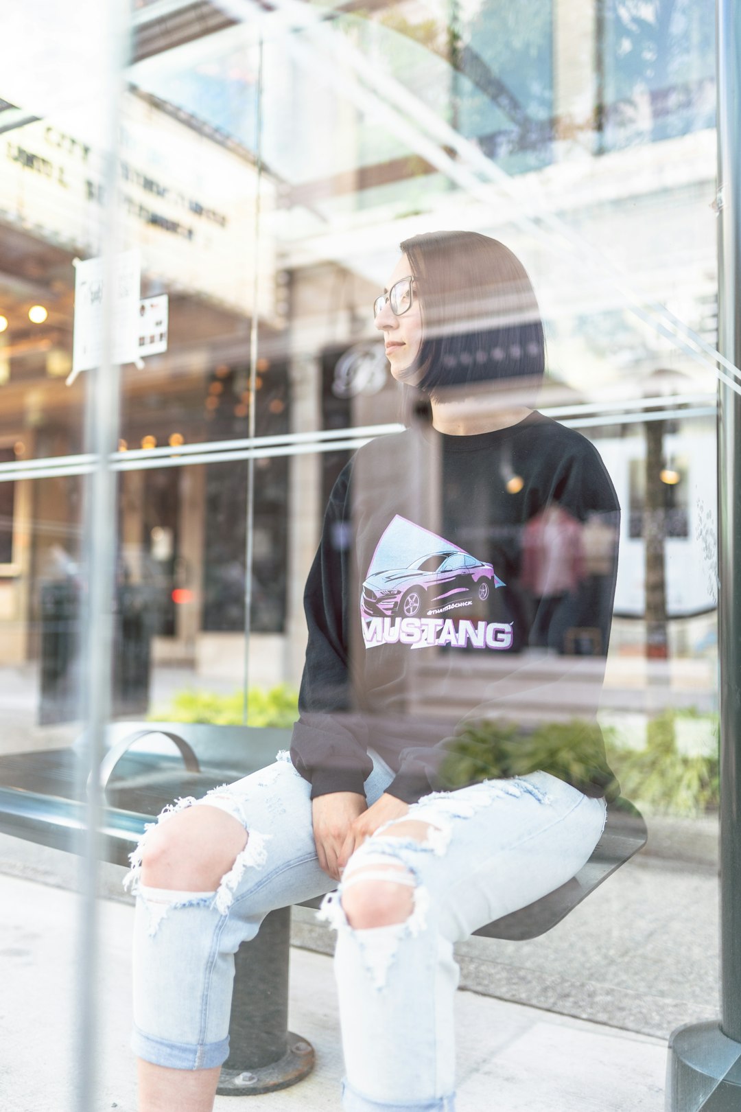 man in black hoodie and white pants sitting on glass window