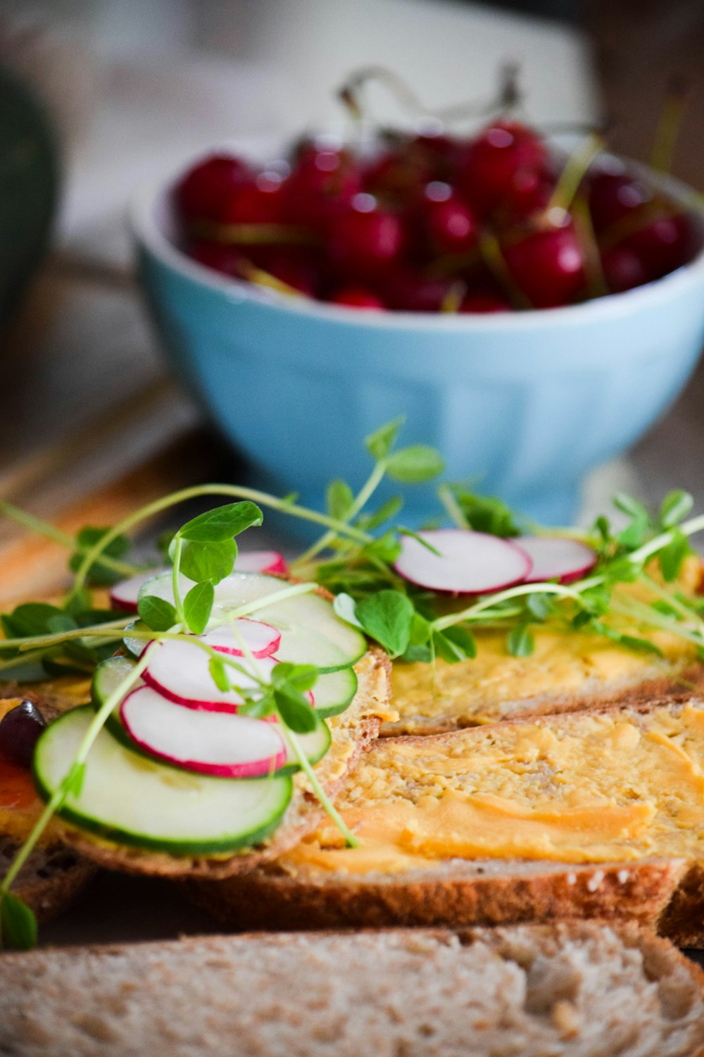 sliced bread with sliced tomato and green leaf vegetable on blue ceramic bowl