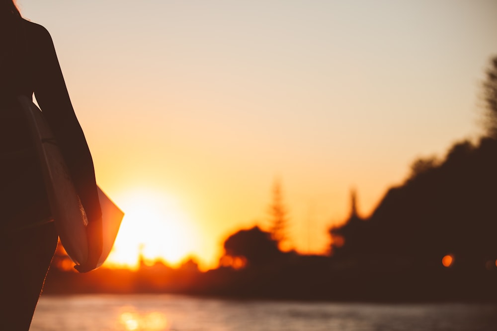 person in black hoodie standing near body of water during daytime