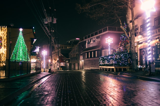 A warmly lit street decorated with subtle dark green and deep red Christmas lights in Sant Just.