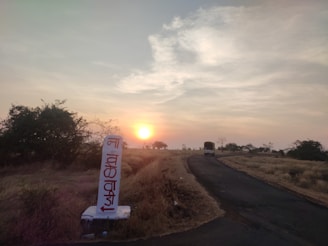 A modern bus from Ajniha Haditha Limited driving along a scenic highway at sunset.