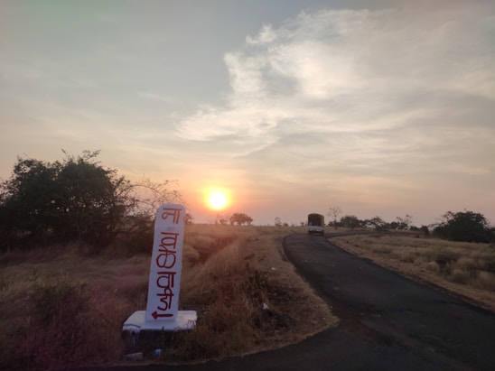 A modern bus from Ajniha Haditha Limited driving along a scenic highway at sunset.