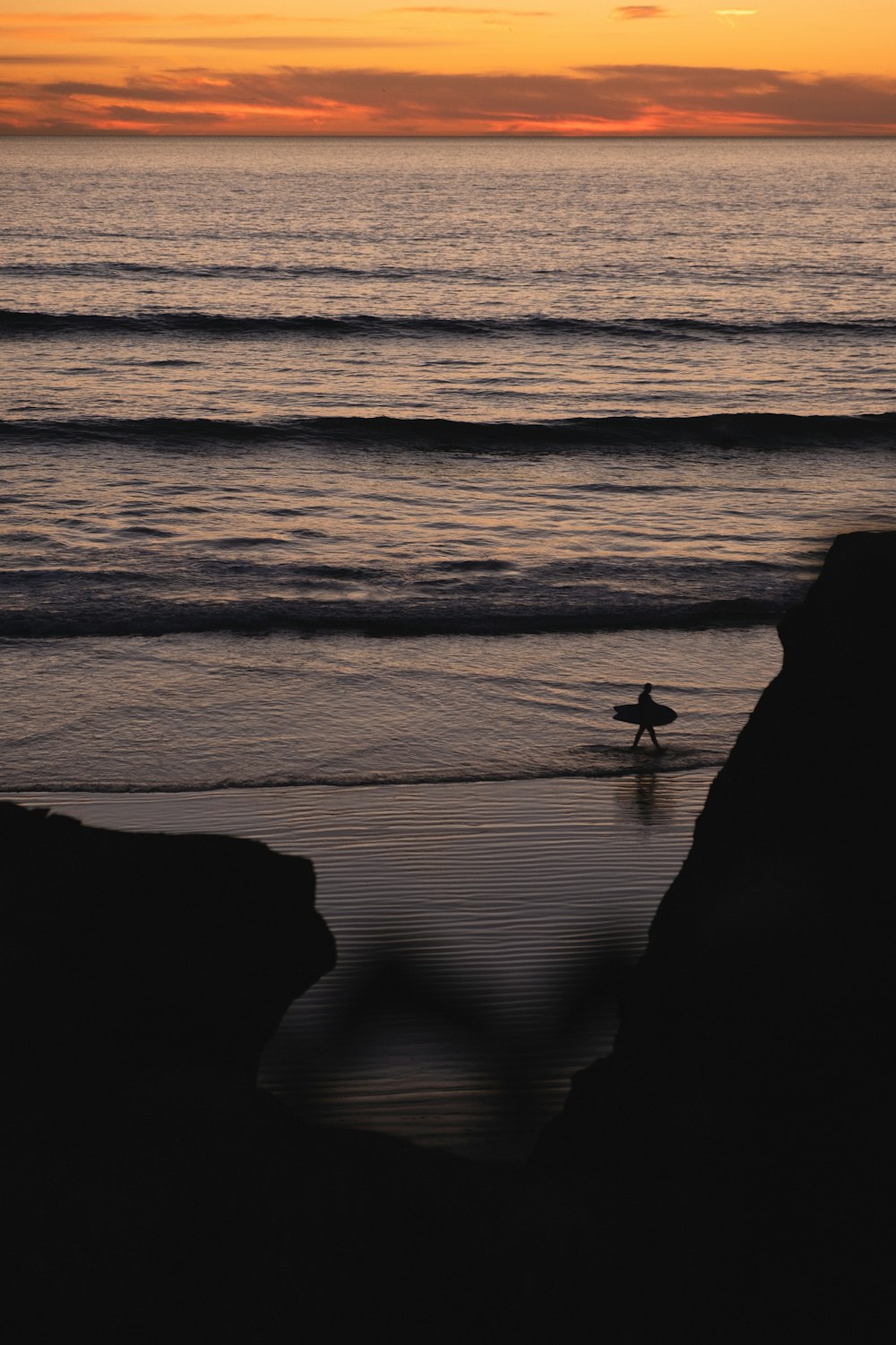 silhouette of 2 people standing on seashore during sunset