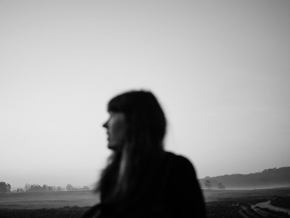 woman in black coat standing on field during daytime