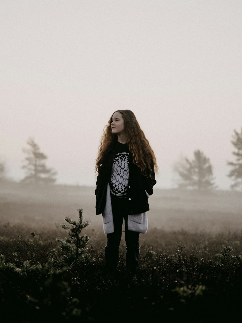 woman in black jacket standing on green grass field during daytime