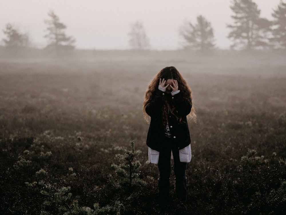 woman in black jacket standing on grass field