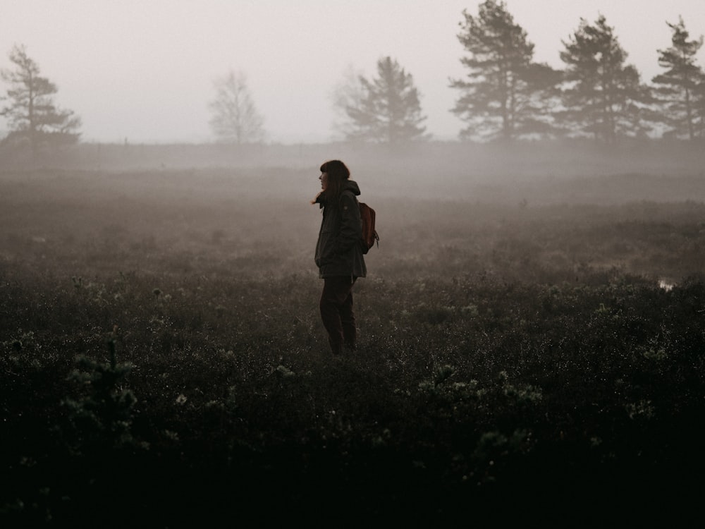 person in black jacket standing on green grass field during daytime