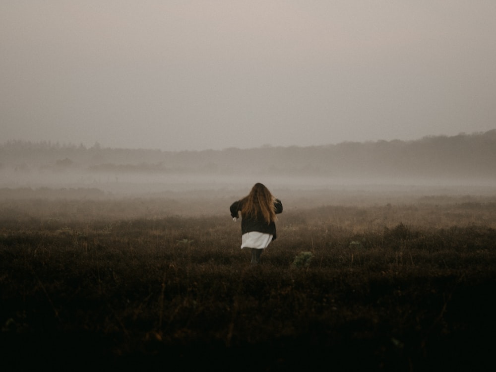 woman in white shirt and black pants standing on grass field