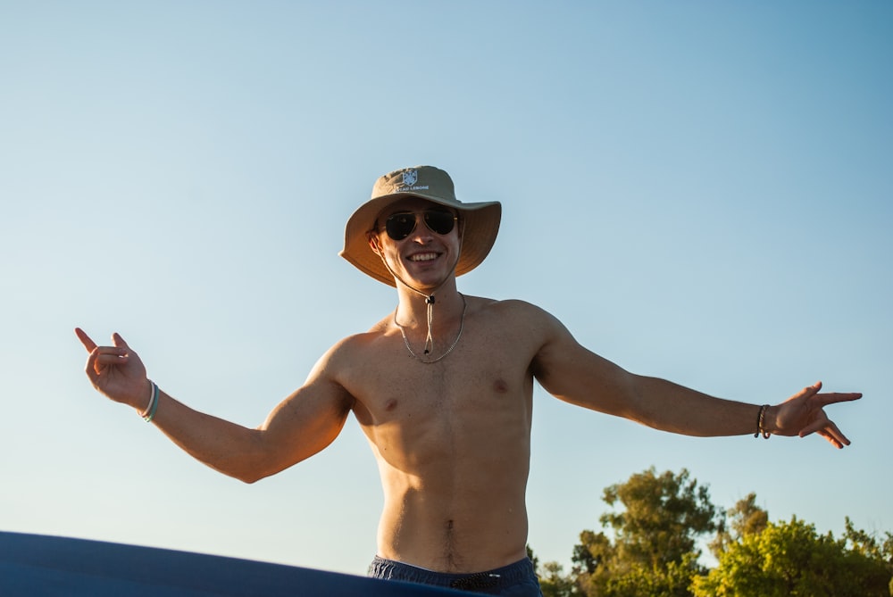 topless man wearing blue denim jeans and brown fedora hat