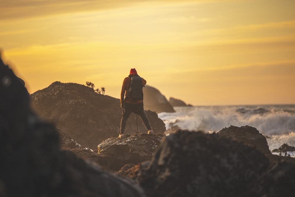 man in black jacket standing on rock formation during daytime