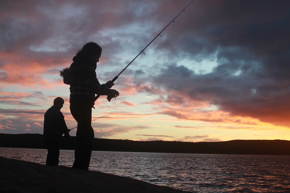 silhouette of 2 person fishing during sunset