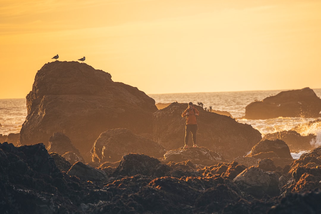 person standing on rock formation near sea during daytime