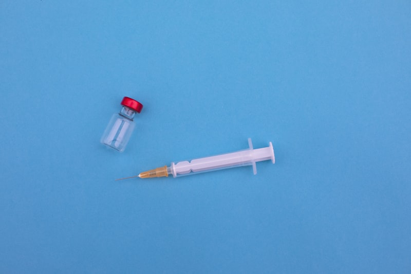 Medical syringe and vaccine vial on a blue background