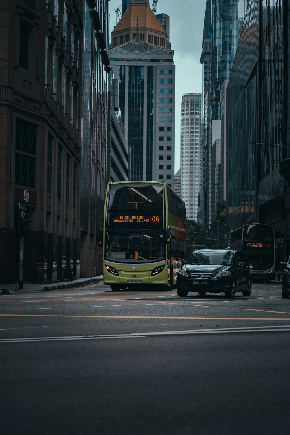 black and yellow bus on road in between high rise buildings during daytime