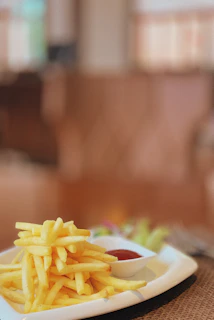 Golden fries freshly cooked and served with a side of ketchup on a wooden table