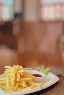 A vibrant plate of golden French fries with ketchup on the side, set on a colorful background.