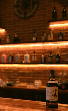 A cozy, dimly lit tasting room with shelves of premium whisky bottles glowing warmly.