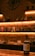 A bottle of whiskey is prominently displayed on a wooden counter in a dimly lit bar with soft amber lighting. The background shows shelves lined with various liquor bottles against a brick wall, creating a warm and inviting atmosphere.