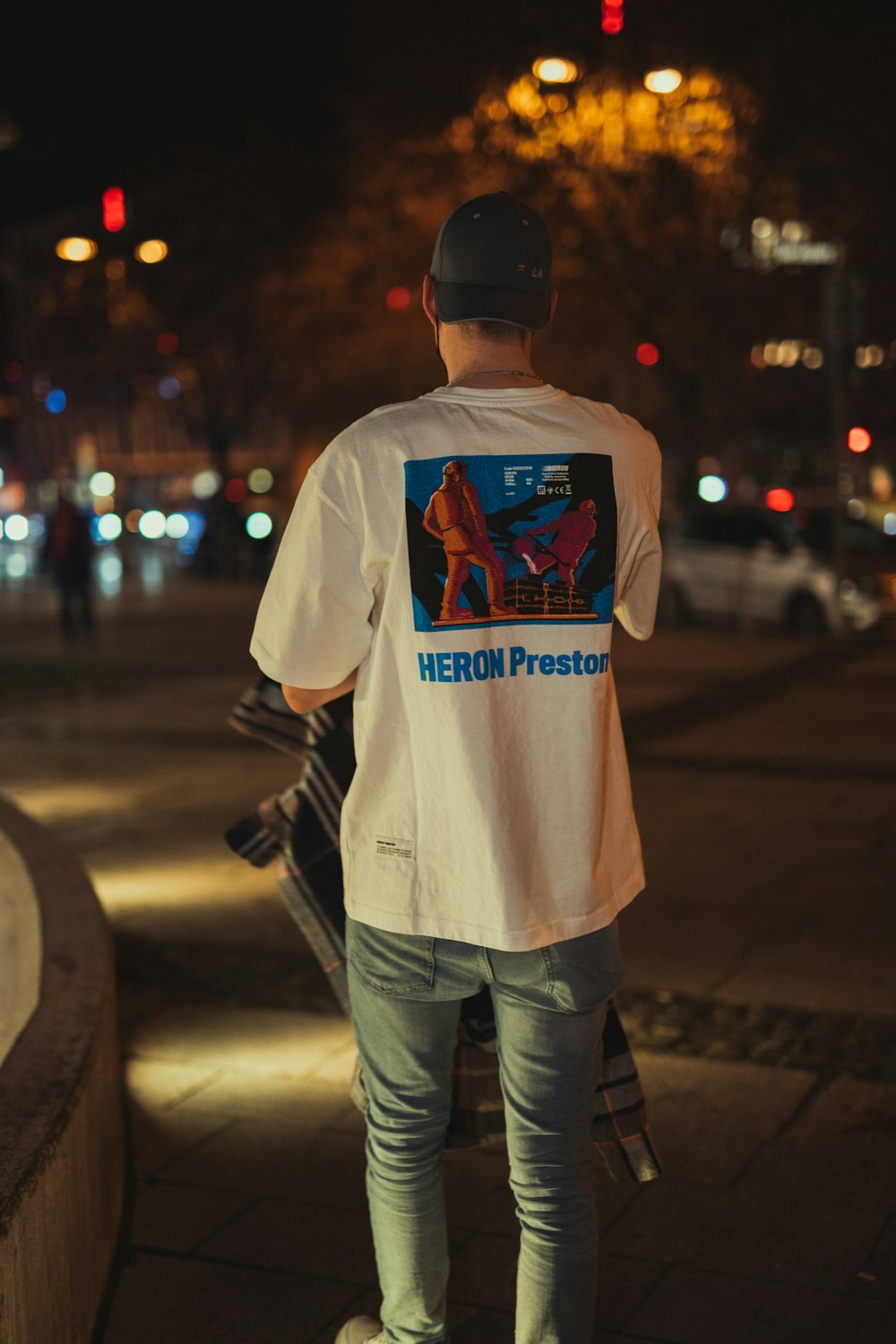 흰 셔츠와 파란 데님 청바지를 입은 남자가 밤 시간 동안 보도에 서 있다