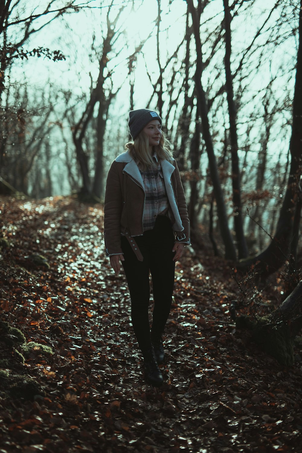 昼間の森に立つ灰色のコートを着た女性