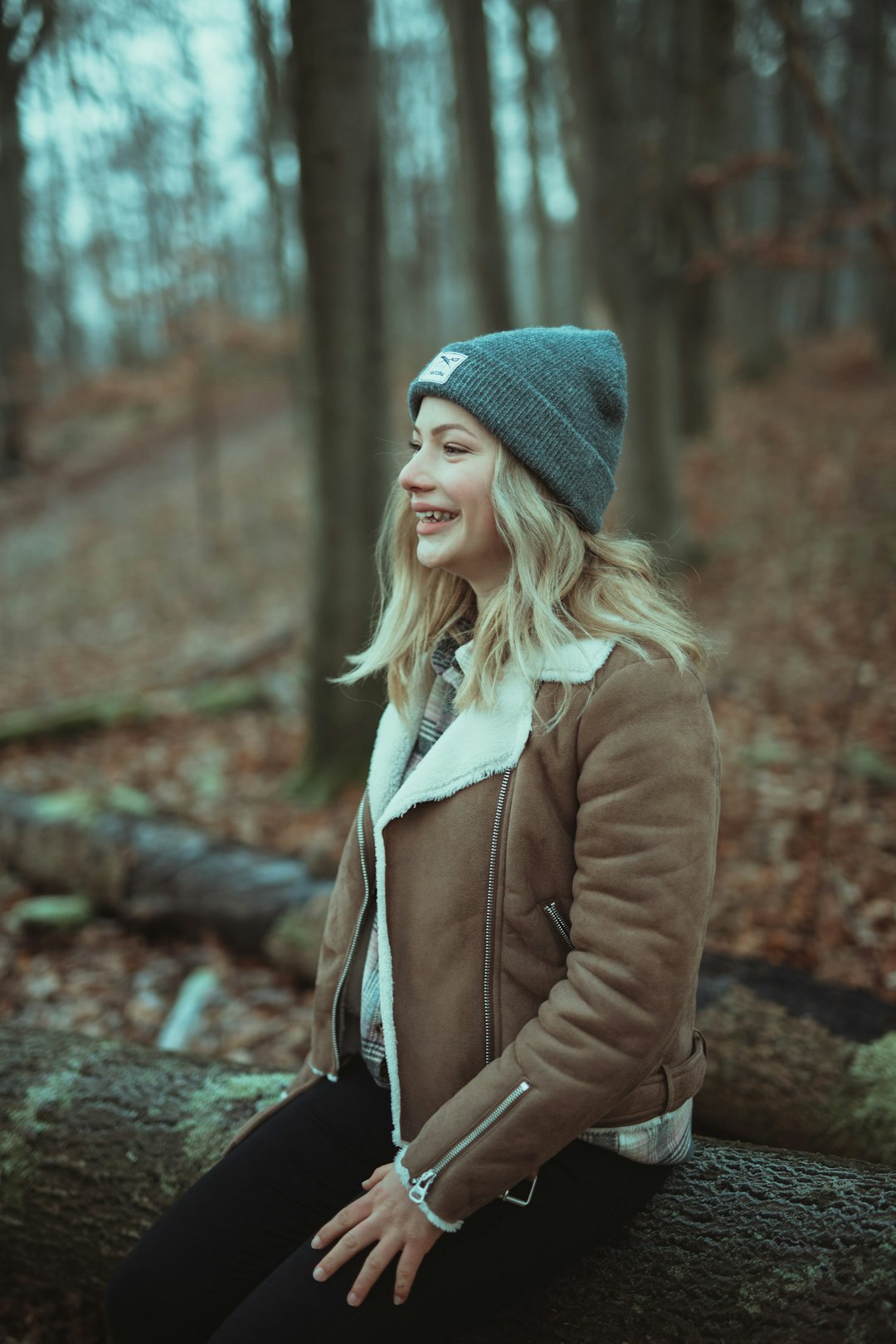 woman in brown coat and blue knit cap standing on brown soil during daytime