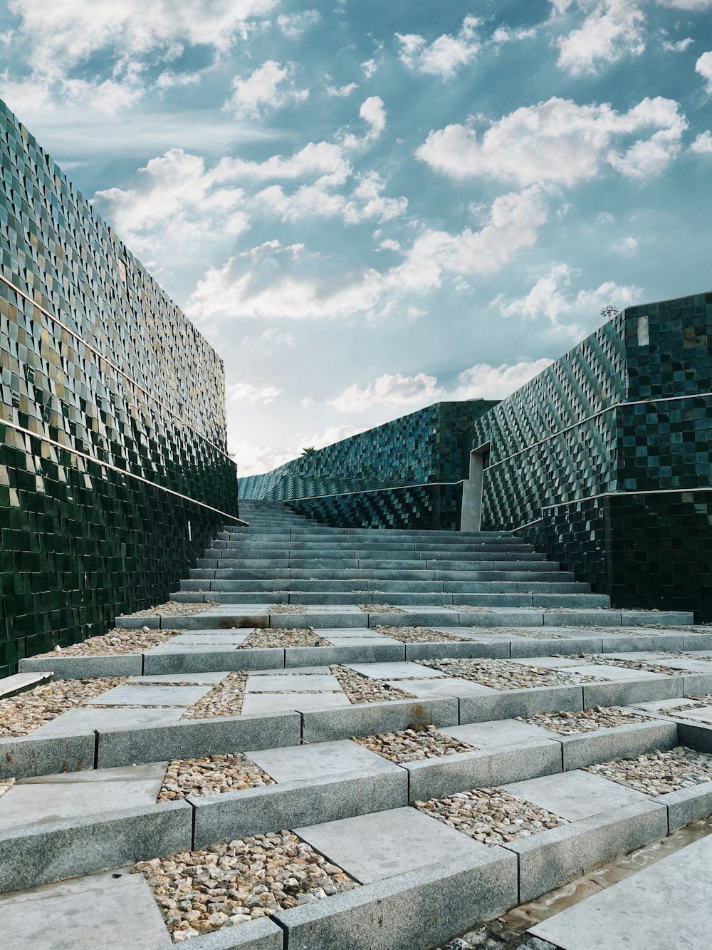 gray concrete pathway between blue glass building under blue sky during daytime