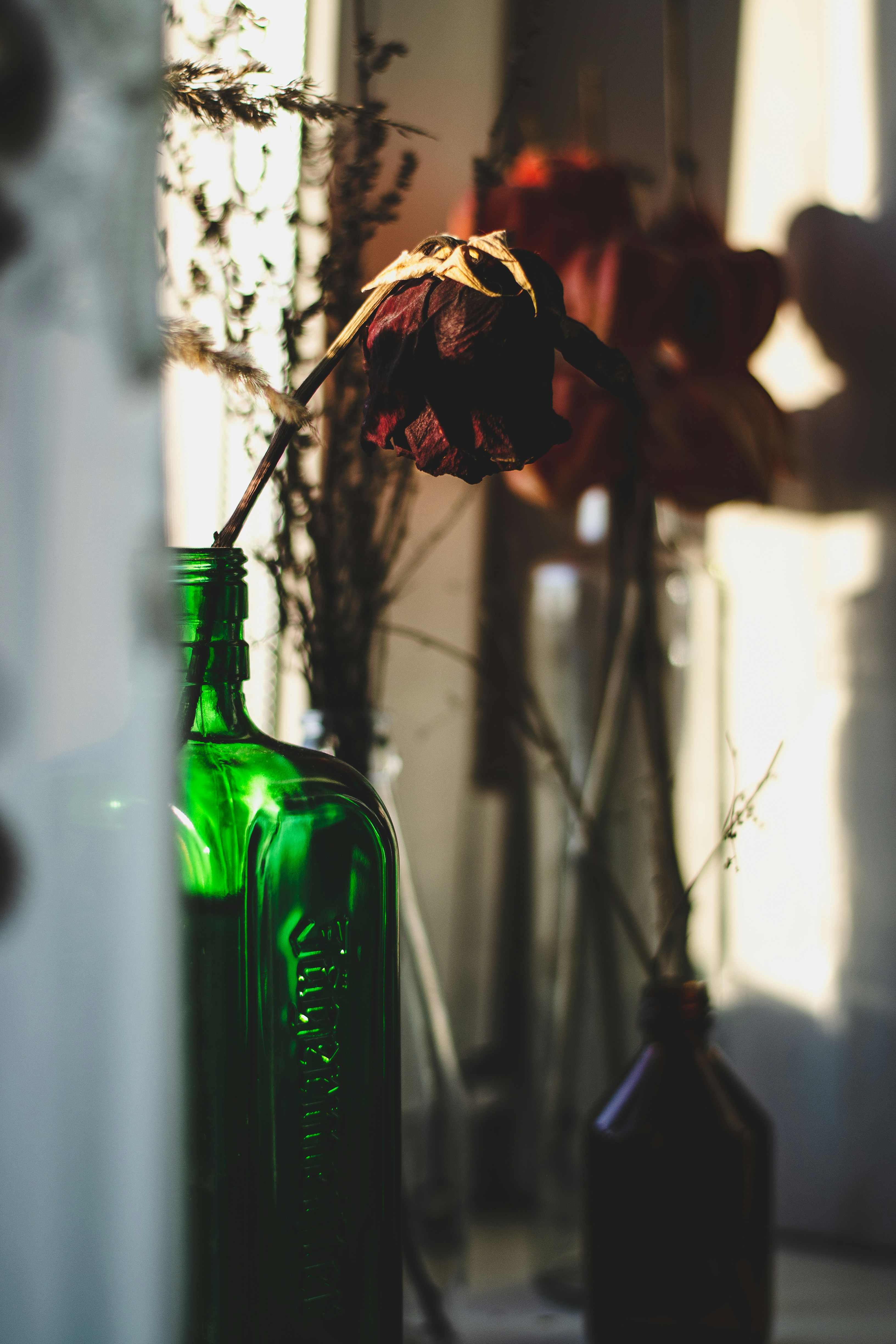 garrafa de vidro verde com flores marrons e vermelhas