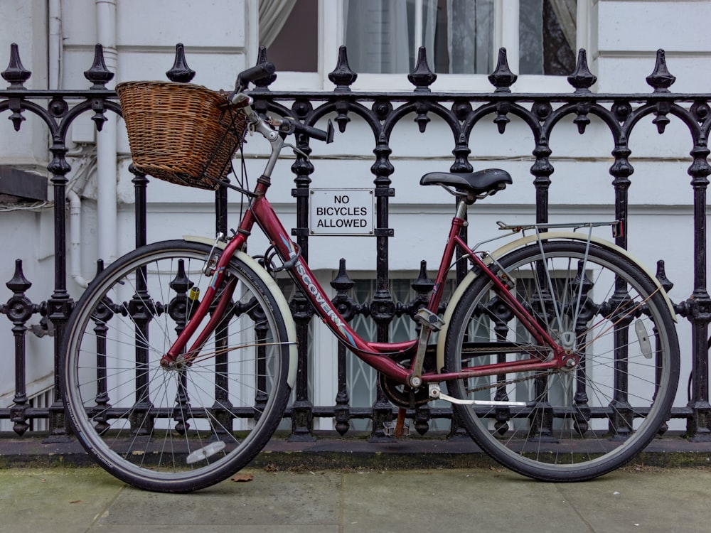 vélo de route rouge et noir garé à côté d’une clôture en métal noir